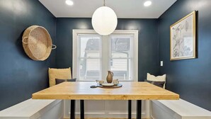 A dining area with a wooden table, black chairs, a hanging light fixture, and a window with blinds. - Close to OSU Rooftop Patio  Grill & Outdoor TV (Columbus)