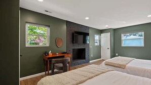 Un dormitorio con dos camas, un escritorio, una chimenea y un televisor.