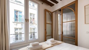 A hotel room with a bed, a window with curtains, and a view of a building outside. - 4#New suite 4 personnes- Saint Germain Notre-Dame (Paris)