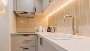 A modern kitchen with a white countertop, a stainless steel range hood, a sink with a modern faucet, and a hexagonal tile backsplash. - 2Bedrooms#6pers#Poissoniers#Paris 18#AC (Paris)
