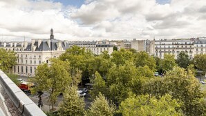 A cityscape with historic architecture, including a prominent building with a dome and a statue.