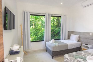 A modern hotel room with a bed, bedside table, and a TV mounted on the wall.