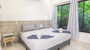 A hotel room with a bed, a nightstand, and a window with curtains.