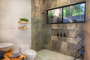A modern bathroom with a shower, toilet, and sink.