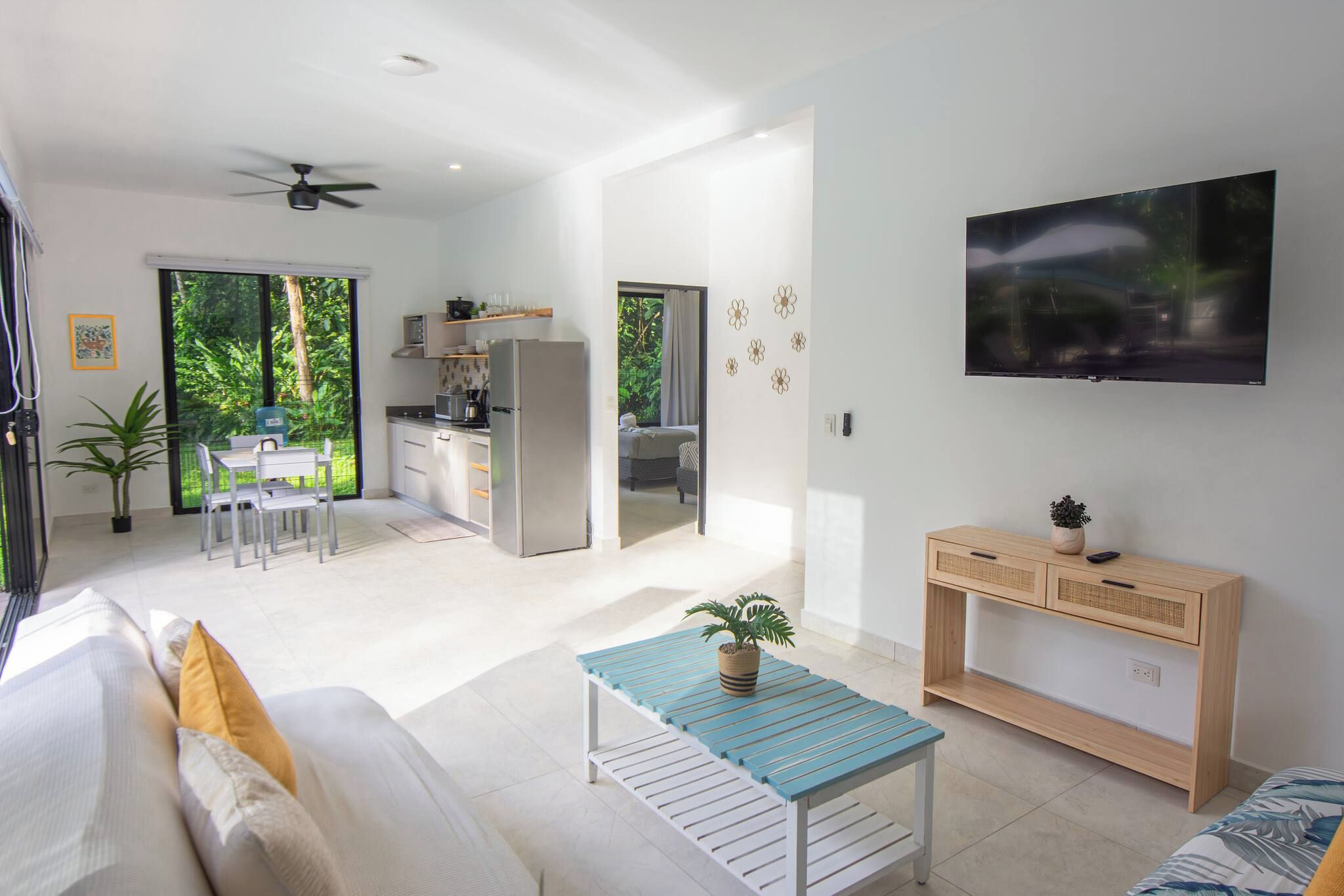 Un espacio habitable moderno con un sofá, una mesa de centro, un televisor y una zona de cocina.