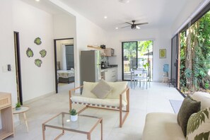 A modern living room with a sofa, coffee table, and a dining area with chairs and a table.