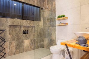 Een moderne badkamer met douche, toilet en een wastafel met handdoekhouder.