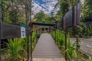 A pathway leading to a building with a wooden deck and a metal fence.