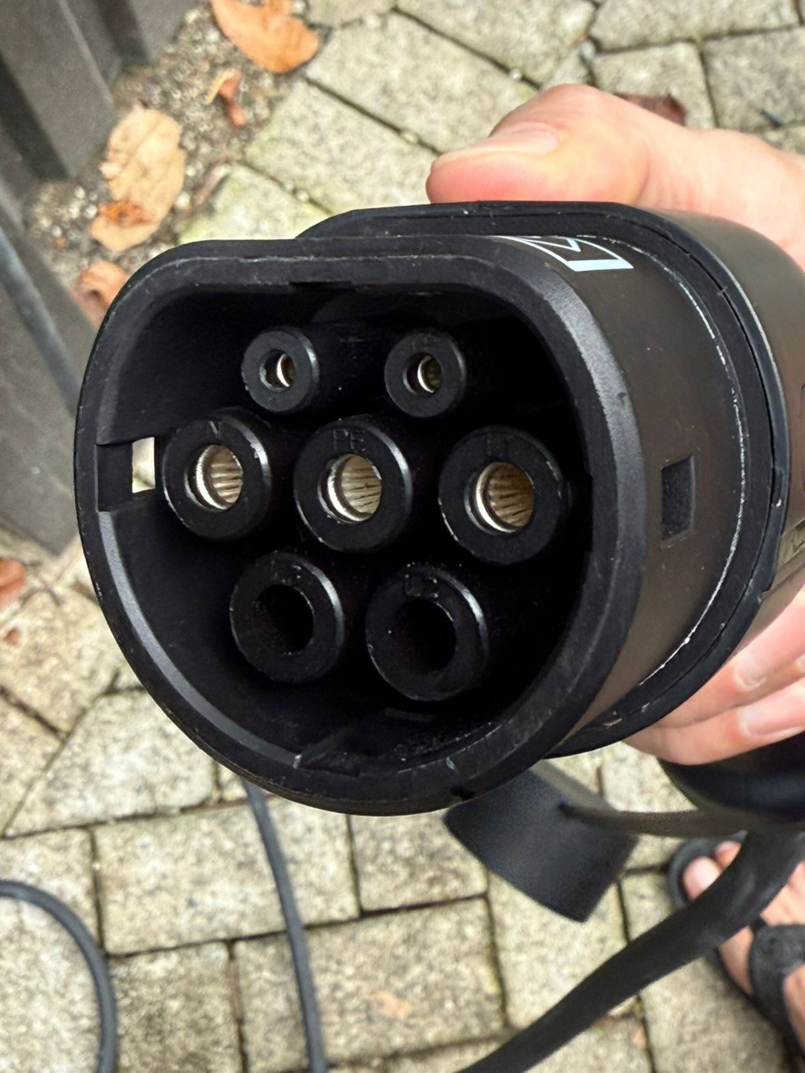 Primer pla d'un endoll elèctric negre amb diverses clavilles i un cable.