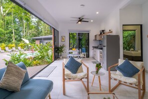 A modern interior with a dining area, kitchen, and seating with a view of the outdoors.