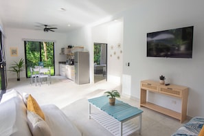 A modern living space with a kitchen, dining area, and a TV mounted on the wall.