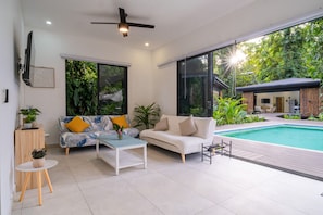 Uma sala de estar moderna com piscina, janelas amplas e ventilador de teto.