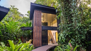 Une maison moderne à deux étages, dotée d’une façade en verre, d’un revêtement extérieur en bois et d’un escalier menant à l’étage supérieur.