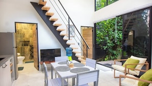 Un intérieur moderne avec un escalier, un coin repas et un espace extérieur aménagé pour s’asseoir.