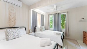 A hotel room with two beds, a ceiling fan, and large windows with curtains. - Multifamily 413 home near beach & plaza (Rincon)