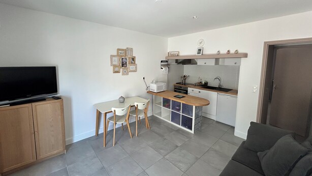 Un espacio habitable compacto con kitchenette, zona de comedor y salón.