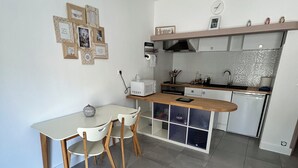 Una cocina compacta con una mesa y sillas, microondas, pileta y un refrigerador pequeño.