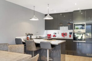A modern kitchen with a central island, dark cabinets, and stainless steel appliances.