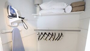 Habitación compacta con plancha integrada, tendedero y una pequeña zona de estar.