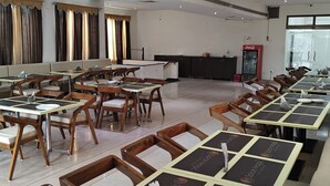 A dining area with tables and chairs, a counter, and a Coca-Cola refrigerator. - Hotel Grand Leela Krishna  (Bhimavaram)