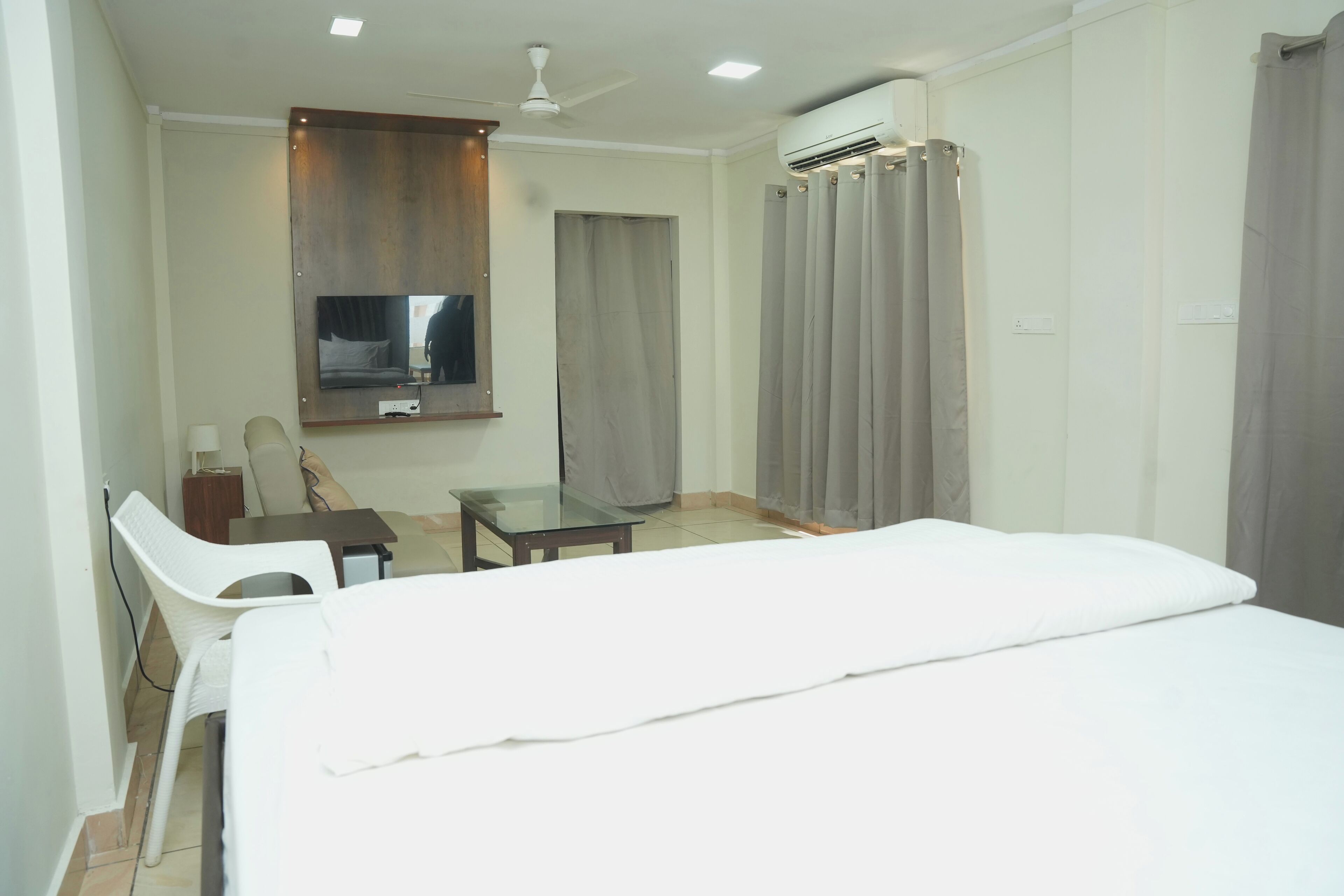 Habitación de hotel con cama, escritorio, silla, televisor y aire acondicionado.