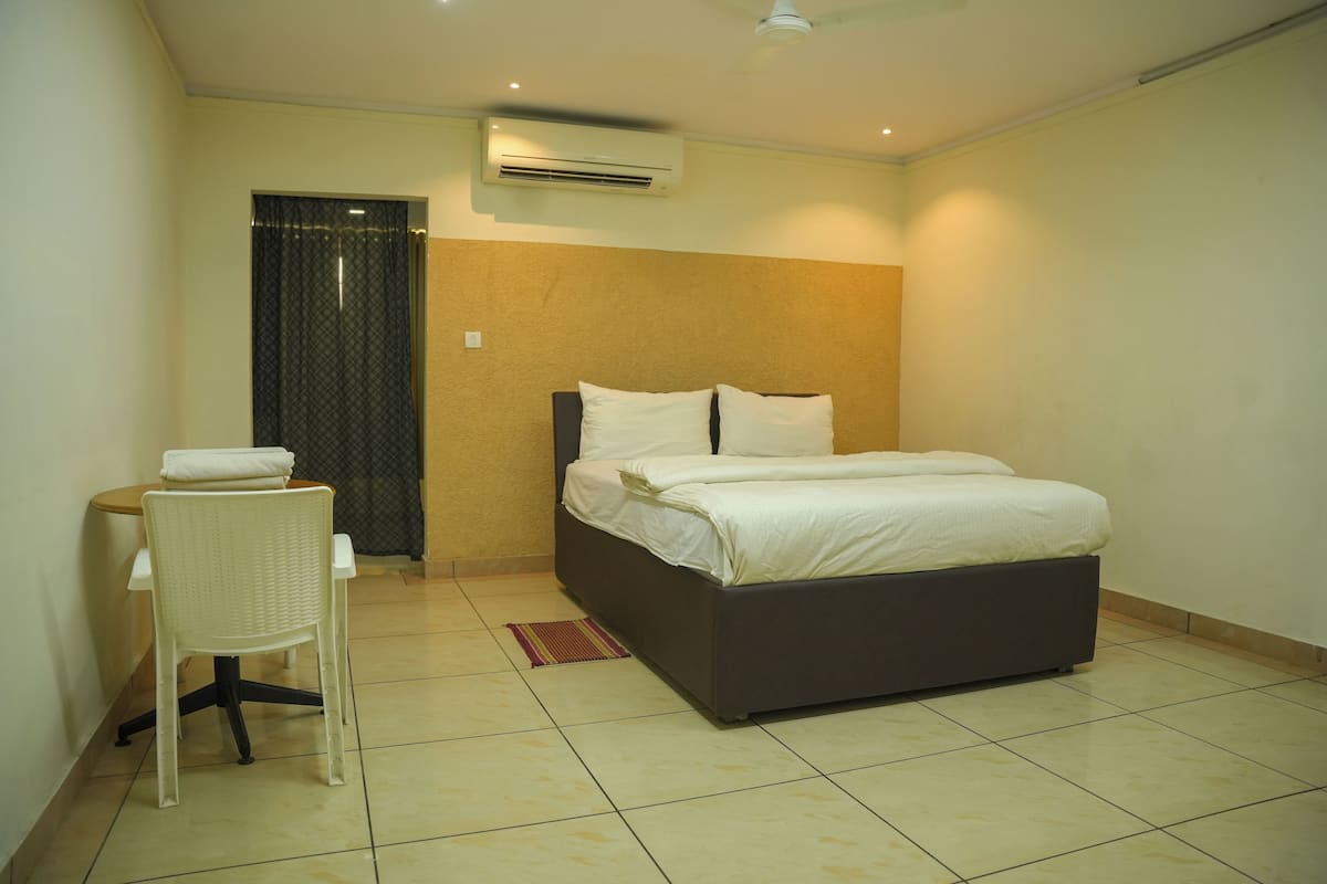A bedroom with a bed, a chair, and an air conditioning unit.
