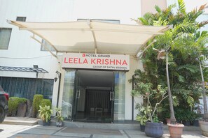 La entrada del Hotel Grand Leela Krishna, con un acceso cubierto y macetas.
