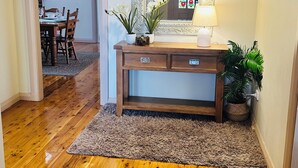 A wooden-floored hallway with a mirror, a lamp, and a potted plant.