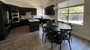 Une cuisine moderne avec des meubles en bois foncé, des appareils électroménagers en acier inoxydable et un îlot central.