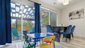 Een kamer met een tafel, stoelen, een bank en een groot raam.