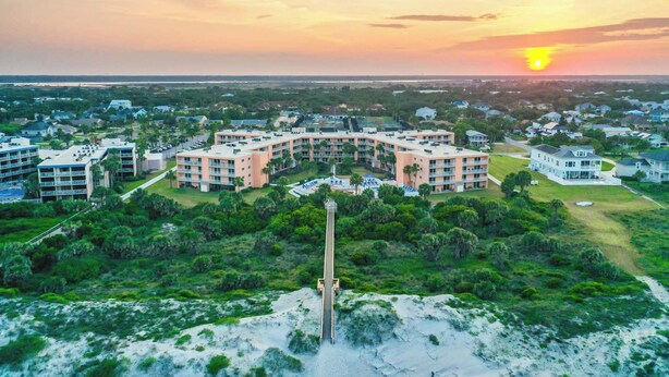 A coastal resort with a central building surrounded by lush greenery and a sandy beach. - Gone Coastal l Steps to Beach l Sleeps 6 (St. Augustine)