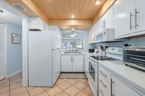 A modern kitchen with white cabinets, a refrigerator, microwave, oven, and a toaster.