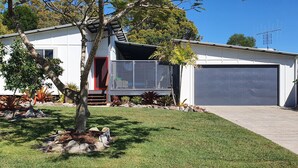 A modern two-story house with a garage, surrounded by a well-maintained lawn and various plants.