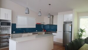 A modern kitchen with white cabinets, a central island, a microwave, a stove, and a refrigerator.