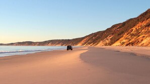Une plage où un véhicule est garé sur le sable, face à l’océan.