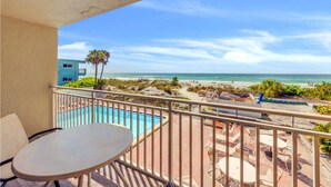 Ein Balkon mit Pool, Sitzgelegenheit im Freien und Blick auf Strand und Meer.