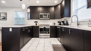 A modern kitchen with dark cabinetry, a stainless steel oven, and a microwave.
