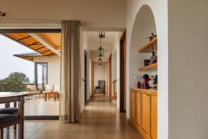 A modern interior with a wooden ceiling, a kitchen with wooden cabinets, a dining area with a table and chairs, and a view through a glass door.