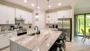 A modern kitchen with white cabinets, stainless steel appliances, a marble island, and pendant lighting. - Golf Days & Beach Fun: Port Charlotte Home w/ Yard (Port Charlotte)