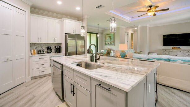 A modern kitchen with white cabinetry, a marble island, stainless steel appliances, pendant lighting, and a ceiling fan. - Golf Days & Beach Fun: Port Charlotte Home w/ Yard (Port Charlotte)