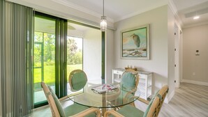 A dining area with a glass table, four chairs, a painting, and a white cabinet. - Golf Days & Beach Fun: Port Charlotte Home w/ Yard (Port Charlotte)