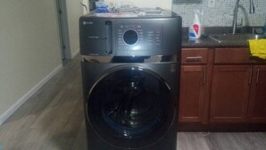 A laundry room with a front-loading washer and dryer, wooden cabinets, and a tiled backsplash in the adjacent kitchen area. - 3 bedroom with free parking (Schenectady)