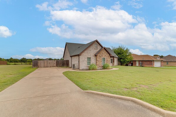 A residential property with a paved driveway, a brick house, and a fenced yard. - 10 Mi to Lake Tawakoni: Family Wills Point Getaway (Wills Point)