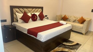 A hotel room with a large bed, a sofa, and a nightstand with a phone.