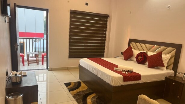 A bedroom with a bed, bedside tables, a chair, a small table, and a trash bin.