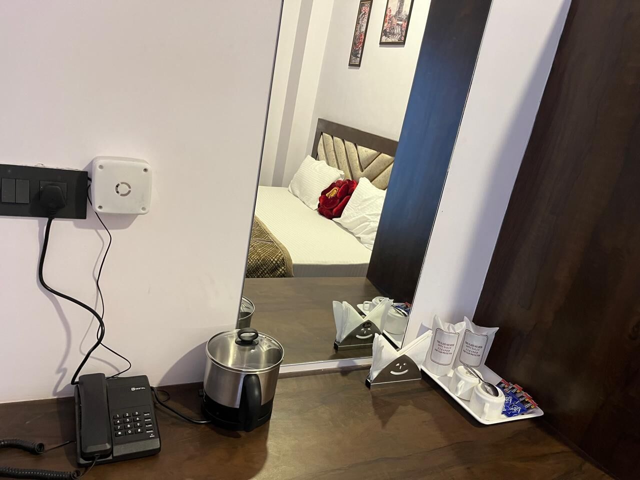 A hotel room with a bed, a coffee maker, a telephone, and a tray with toiletries.