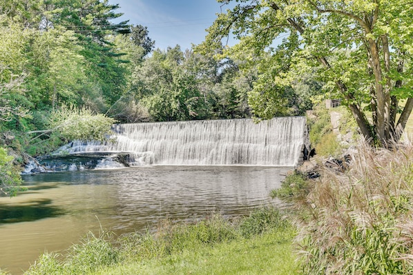 A waterfall cascading into a calm pond surrounded by lush greenery.