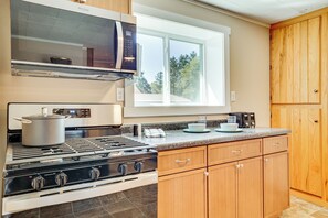 A kitchen with a stove, microwave, and wooden cabinets. - Jackson County ATV Trail Access: Merrillan Home! (Merrillan)