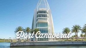 Un edificio moderno con un original diseño triangular, rodeado de palmeras y una masa de agua.