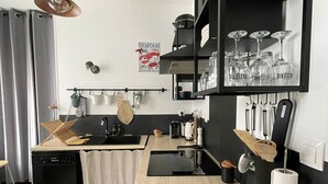 A modern kitchen with a wooden countertop, black cabinets, and a hanging light fixture.